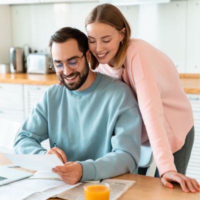 couple smiling and looking at piece of mail in home