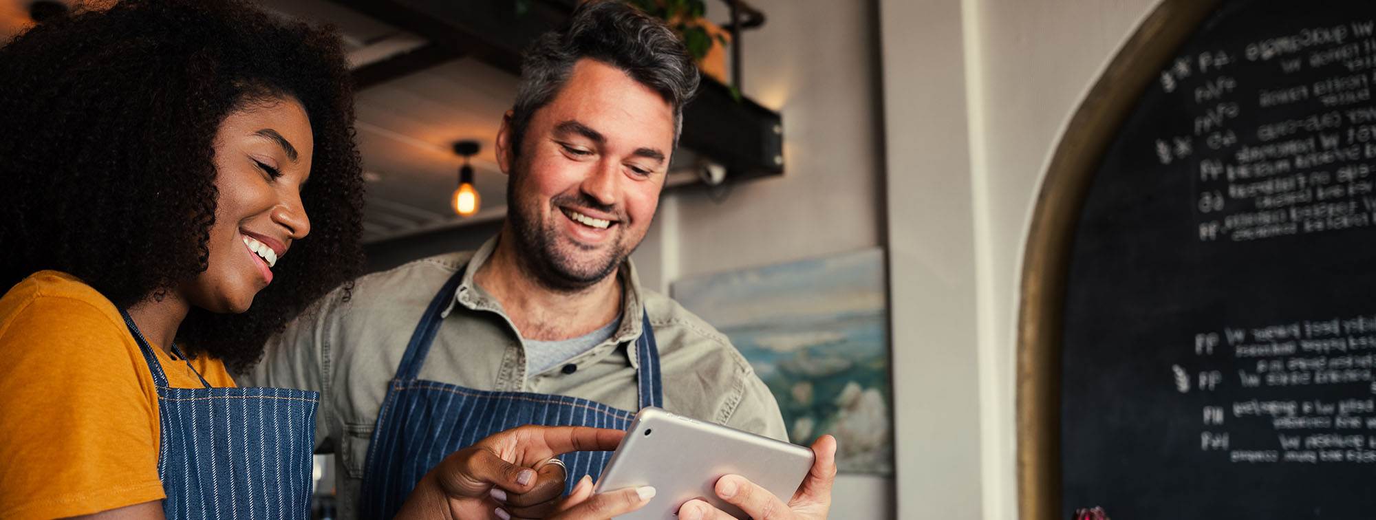 Two baristas looking at a tablet