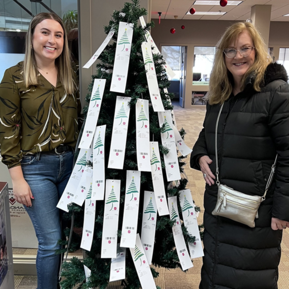 Financial plus staff in front of Christmas donation tree