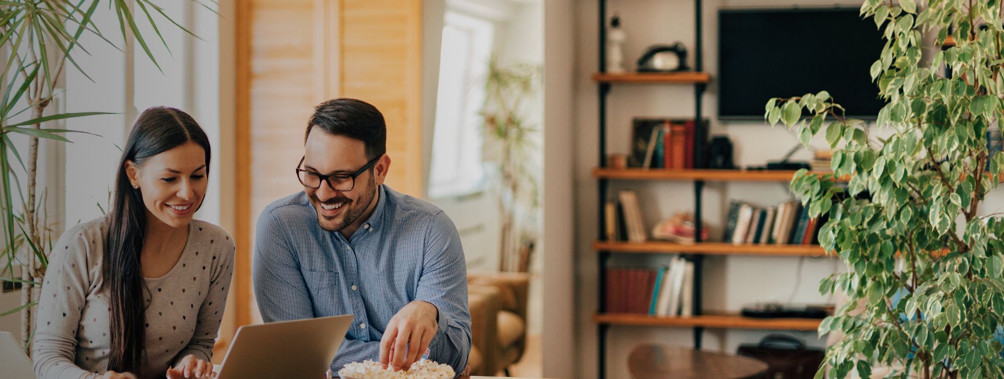 couple in home smiling and looking at laptop