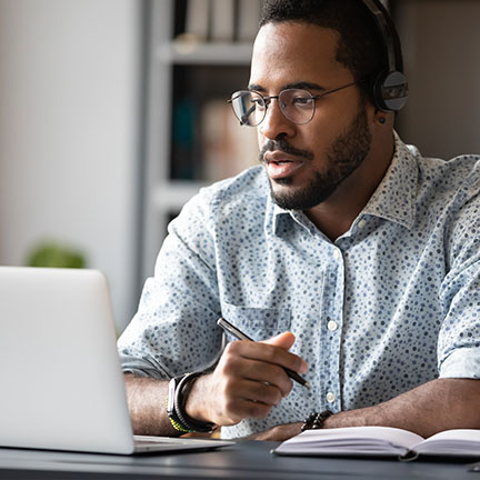 Man taking notes as he reads off the computer